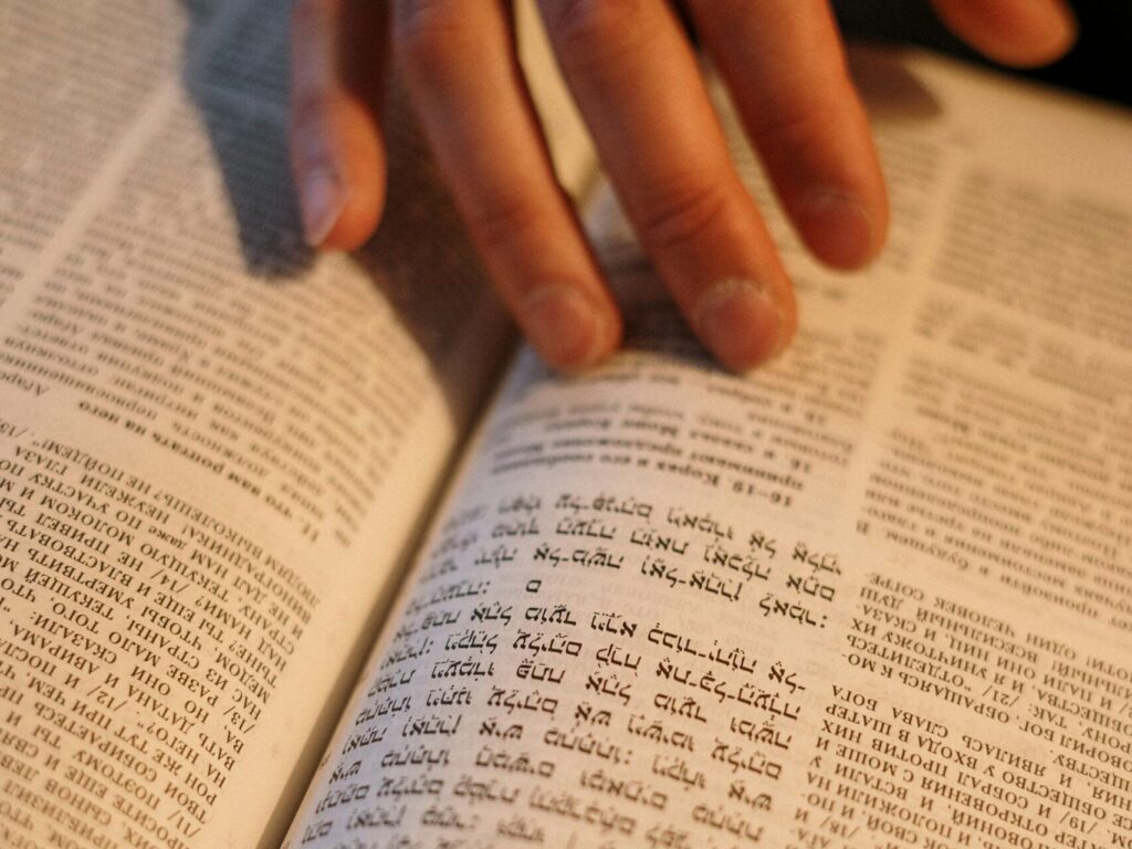 A close-up image of a hand turning pages in a Hebrew religious book, focused on Jewish tradition.
