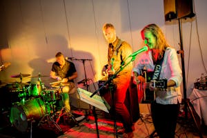 Lively band performing with guitars and drums under colorful stage lights.